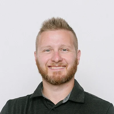 Chiropractor Marcus Kasper Smiling In Front Of White Wall